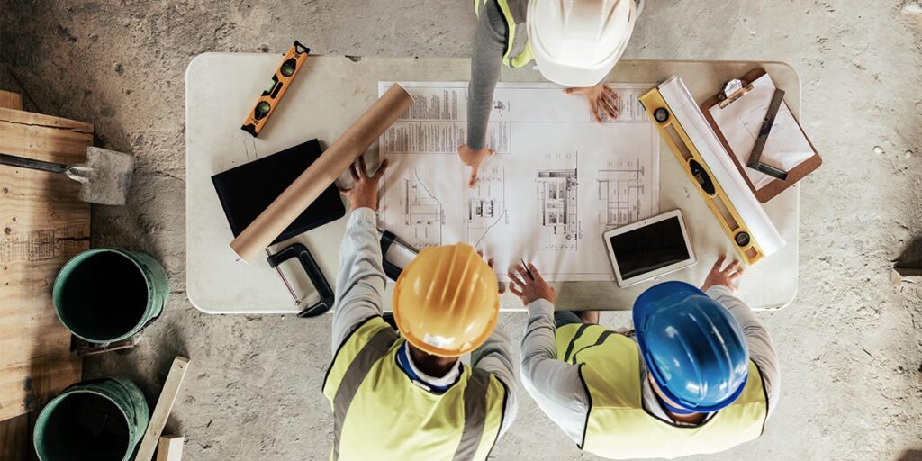 Construction workers reviewing building plans on table